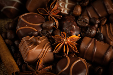 Assortment of white, dark, and milk chocolate. Chocolate with cream, nuts, almonds, hazelnuts and cinnamon with coffee beans. Sweet food and no diet concept.