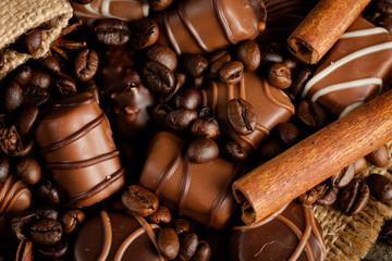 Assortment of white, dark, and milk chocolate. Chocolate with cream, nuts, almonds, hazelnuts and cinnamon with coffee beans. Sweet food and no diet concept.