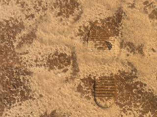 Trekking boots footprints on wet sand. Imprint of rubber boots on sand.