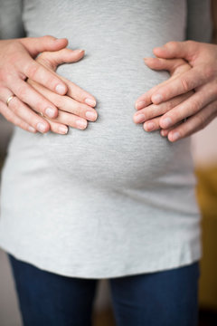 Close Up Of Male And Female Hands Resting On Pregnant Womans Stomach