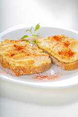 Two open sandwiches with hummus and paprika powder on plate