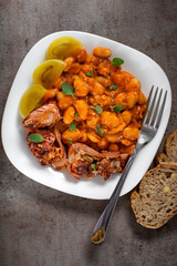 Beans stew with pork ribs and pickles on a white plate