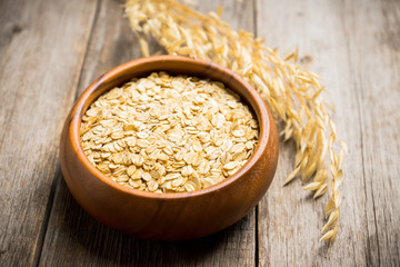 Wooden bowl with uncooked oats on the rustic wooden background. Selective focus. Shallow depth of field.