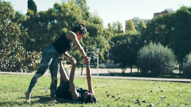 Beautiful couple practicing acro yoga in the morning on the grass lawn. Balance and connection concept.