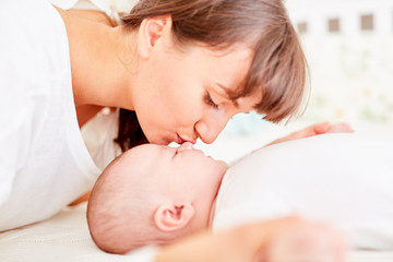Fototapeta na wymiar Mutter gibt ihrem Baby einen Kuss auf die Stirn