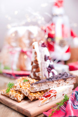 Traditional Italian Christmas fruit cake Panettone Pandoro with festive red ribbon and sweets from nuts and nougat. On a wooden background. Free space for text.