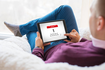 Man looking at calendar on January 1st and reading New Years resolution.