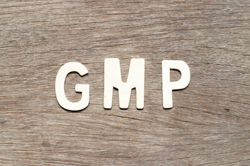 Alphabet letter in word GMP (Abbreviation of good manufacturing practice) on wood background