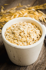 Bowl with uncooked oats on the rustic wooden background. Selective focus. Shallow depth of field. 