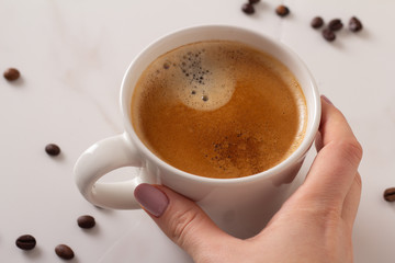 female hand holding a cup of coffee close up.