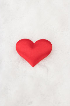 Vertical image of red heart is on white snow background. Concept: love.