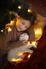 Child girl and white cat under Christmas tree real