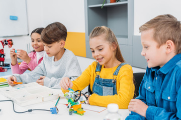 schoolchildren making electric robot at desk in stem education class