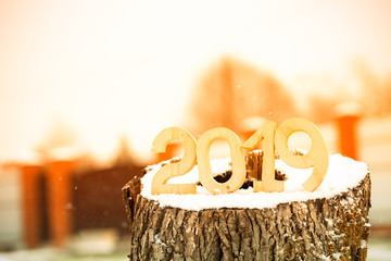 Wooden figures 2019 on the snowy stump. New year and christmas theme. Toned