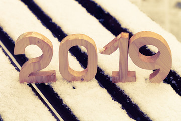Wooden figures 2019 on the snowy bench. New year and christmas theme. Toned