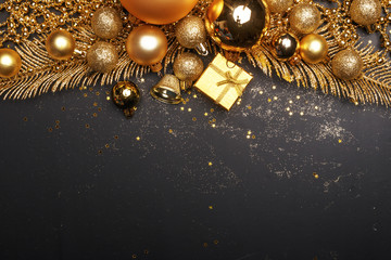 Christmas composition of golden Christmas toys and decoration elements on a black background.