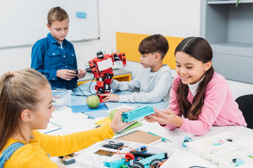 happy schoolchildren working on robot at STEM robotics lesson
