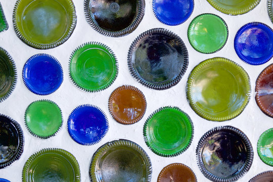 twenty circular bottoms of Glass Bottles used as building materials built into a white wall