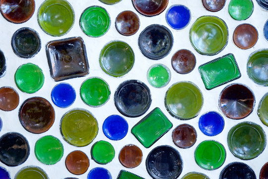 fifty circular bottoms of Glass Bottles used as building materials built into a white wall