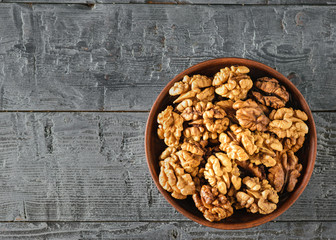 Split walnuts in a clay Cup on a wooden table. The view from the top. Flat lay.