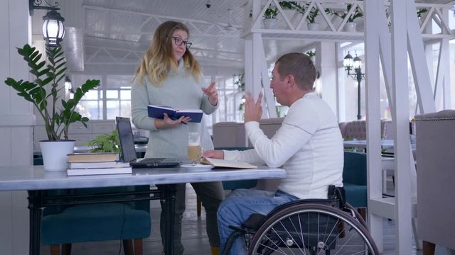 training for invalid, happy sick student mature men in wheelchair with educator female using smart computer technology during personal lecture indoors