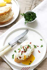 Crispy baguette toasts with cottage cheese, poached egg and dried tomatoes on a light background.