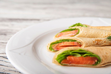Pancakes with salmon and lettuce on a white plate close-up