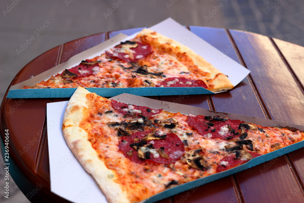 Wall mural Two pieces of pizza on a wooden table