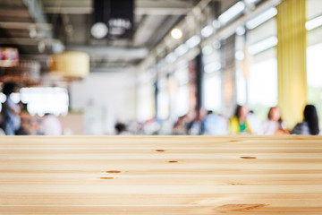 a wooden table with background of blurry modern cafe restaurant interior in a bright day light