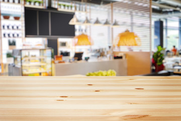 a wooden table with background of blurry modern cafe restaurant interior in a bright day light