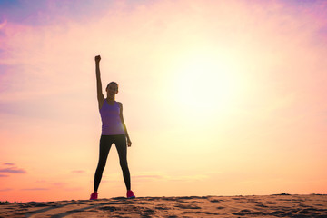 Happy woman celebrating success, silhouette against colorful sky with sunlight.