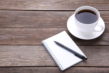 Notebook and cup of coffee on grey wooden background