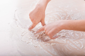 children's hands draw patterns of white flour on the table. baking preparation stage. little game