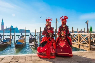  Couple wearing venitian carnival mask in front of gondolas in Grand Canal during Venice carnival in Italy © Maresol