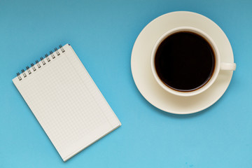 Obraz na płótnie Canvas cup of coffee and notebook on table