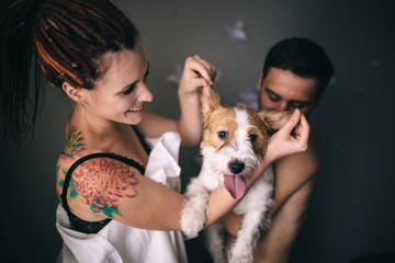 Cheerful and happy couple and the dog, smiling and showing tongue. Love story concept.
