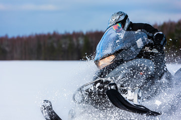 In deep snowdrift snowmobile rider driving fast. Riding with fun in white snow powder during backcountry tour. Extreme sport adventure, outdoor activity during winter holiday on ski mountain resort. - obrazy, fototapety, plakaty