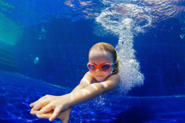 Happy family in swimming pool. Smiling child in goggles swim, dive in pool with fun - jump deep...