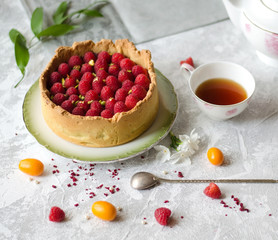 Cheesecake decorated with raspberries on a saucer. Cup of black tea.