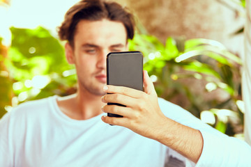 Man using cellphone while working on laptop outdoors.