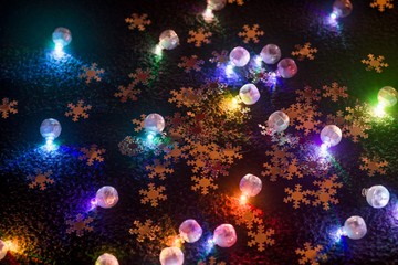 Obraz na płótnie Canvas Shining multicolored bulbs and snowflakes on dark backgound.