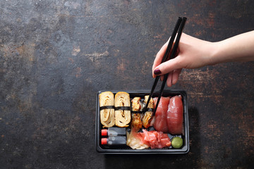 Obiad na wynos, tacka sushi. Jedzenie sushi pałeczkami prosto z tacki. - obrazy, fototapety, plakaty