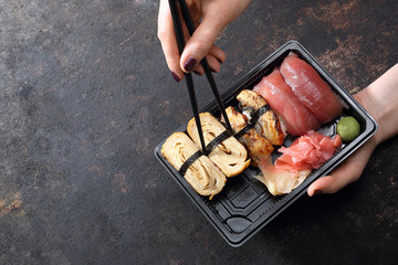 Sushi na wynos.  Jedzenie sushi pałeczkami prosto z tacki.