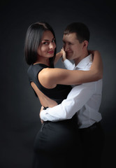 Young beautiful woman in black dress and man in white shirt dancing tango.