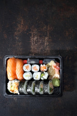 Sushi na wynos. Tacka z kawałkami sushi , imbirem , wasabi i sosem sojowym na ciemnym tle. - obrazy, fototapety, plakaty