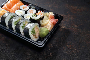 Sushi. Jedzenie na wynos. Tacka z kawałkami sushi , imbirem , wasabi i sosem sojowym na ciemnym tle. - obrazy, fototapety, plakaty