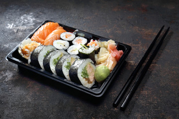 Tradycyjna kuchnia japońska, sushi. Tacka z kawałkami sushi , imbirem , wasabi i sosem sojowym na ciemnym tle.