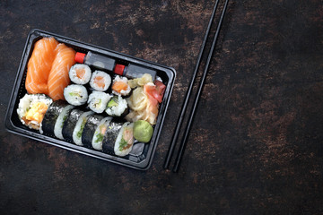 Sushi. Tacka z kawałkami sushi , imbirem , wasabi i sosem sojowym na ciemnym tle w kompozycji z pałeczkami. - obrazy, fototapety, plakaty