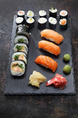 Japońskie sushi. Apetyczne, różnorodne sushi na kamiennym talerzu. Kompozycja na ciemnym tle.