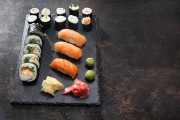 Zestaw sushi. Apetyczne, różnorodne sushi na kamiennym talerzu. Kompozycja na ciemnym tle. - obrazy, fototapety, plakaty